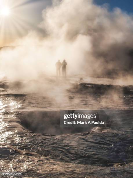 iceland geysir with two people amongst the steam in the background - strokkur stock pictures, royalty-free photos & images