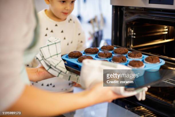 mother baking muffins - cupcake holder stock pictures, royalty-free photos & images