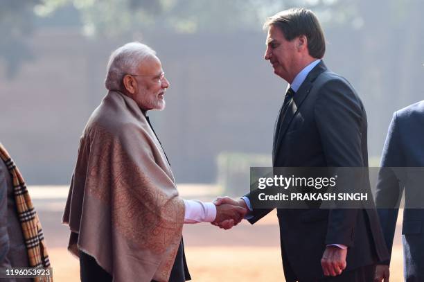 Brazil's President Jair Bolsonaro shakes hands with Indian Prime Minister Narendra Modi during a ceremonial reception at the Presidential palace in...