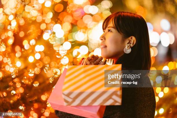 verticale de jeune femme retenant des sacs à provisions la nuit - gift japan photos et images de collection