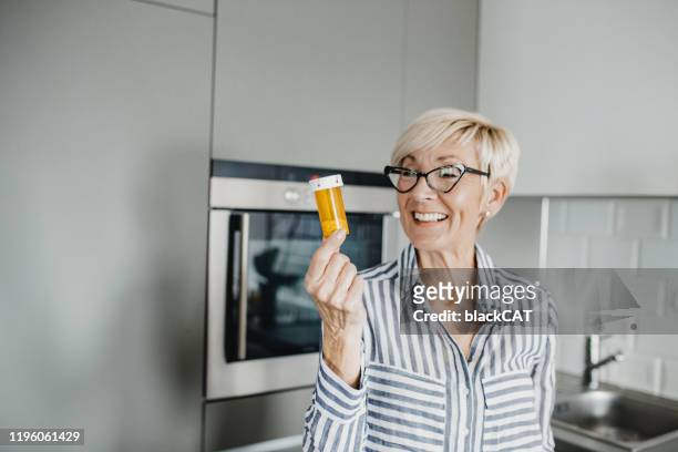 senior woman holding medicines - medicine bottle stock pictures, royalty-free photos & images