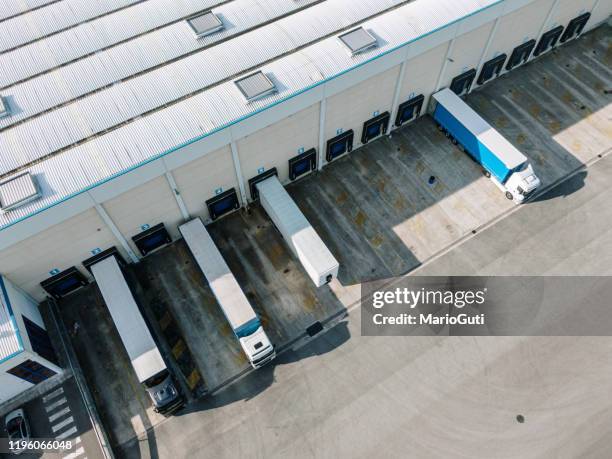 distribution warehouse with loading docks and trucks as seen from above - wide load stock pictures, royalty-free photos & images