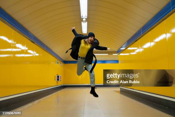 young blonde girl in the subway with hat and black clothes waiting for the subway with yellow background jumping - madrid metro stock pictures, royalty-free photos & images
