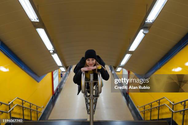 young blonde girl in the yellow subway with hat and black clothes on the stairs climb on the railing - looking at subway map stock pictures, royalty-free photos & images