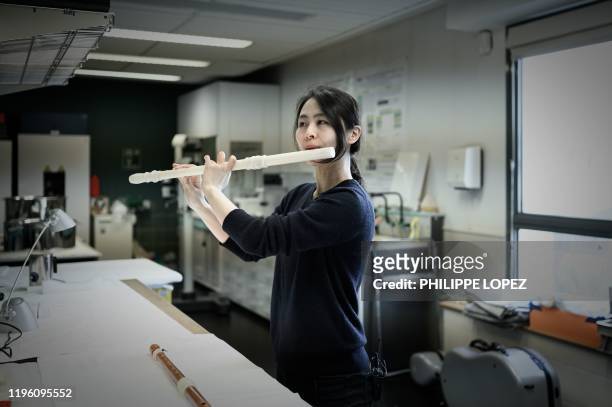 Musician Mina Jang plays the 3D-printing replica of a wooden transverse flute at the music lab of the Music Museum at the Philharmonie in Paris on...