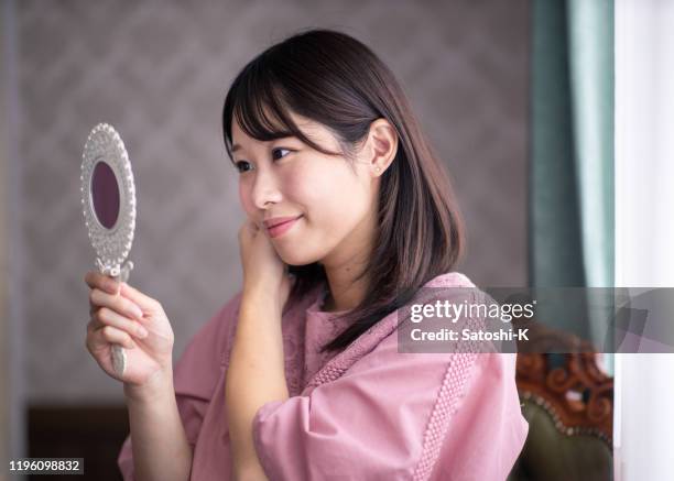 junge frau, die in ihrem hauszimmer aufholt - handspiegel stock-fotos und bilder