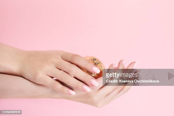closeup of hands of a young woman with pink manicure on nails isolated on white background - french culture stock-fotos und bilder