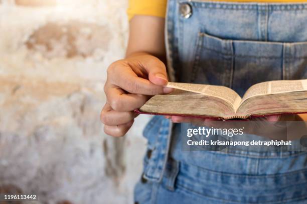 closeup of an unrecognizable person's hands held over a bible at home during the day - biography foto e immagini stock