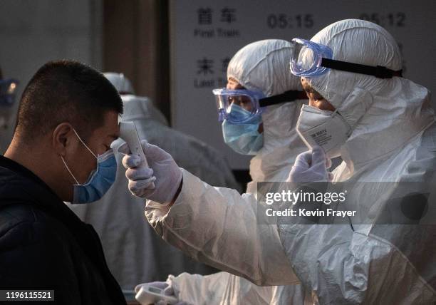 Chinese health worker checks the temperature of a woman entering a subway station during the Chinese New Year and Spring Festival on January 25, 2020...