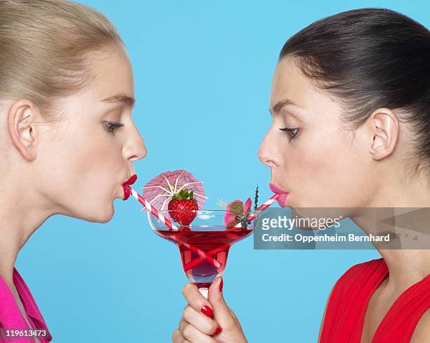 two women sharing a cocktail using two straws - rietje stockfoto's en -beelden
