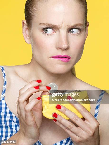 worried looking woman dropping coins in her purse - gierig stockfoto's en -beelden