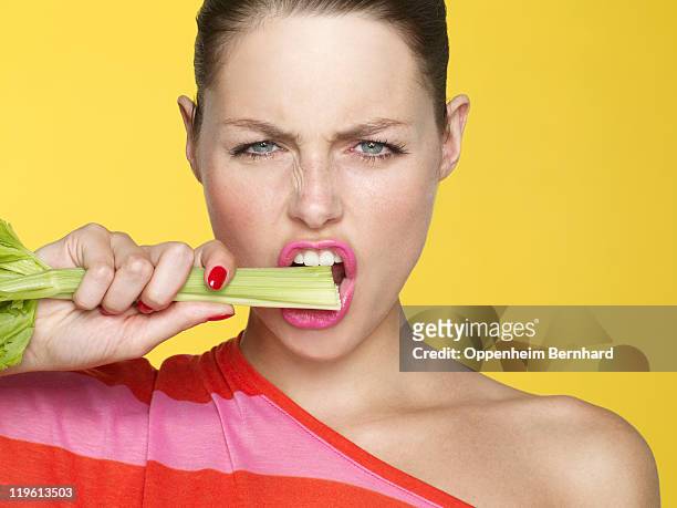 young woman eating celery stick - セロリ ストックフォトと画像