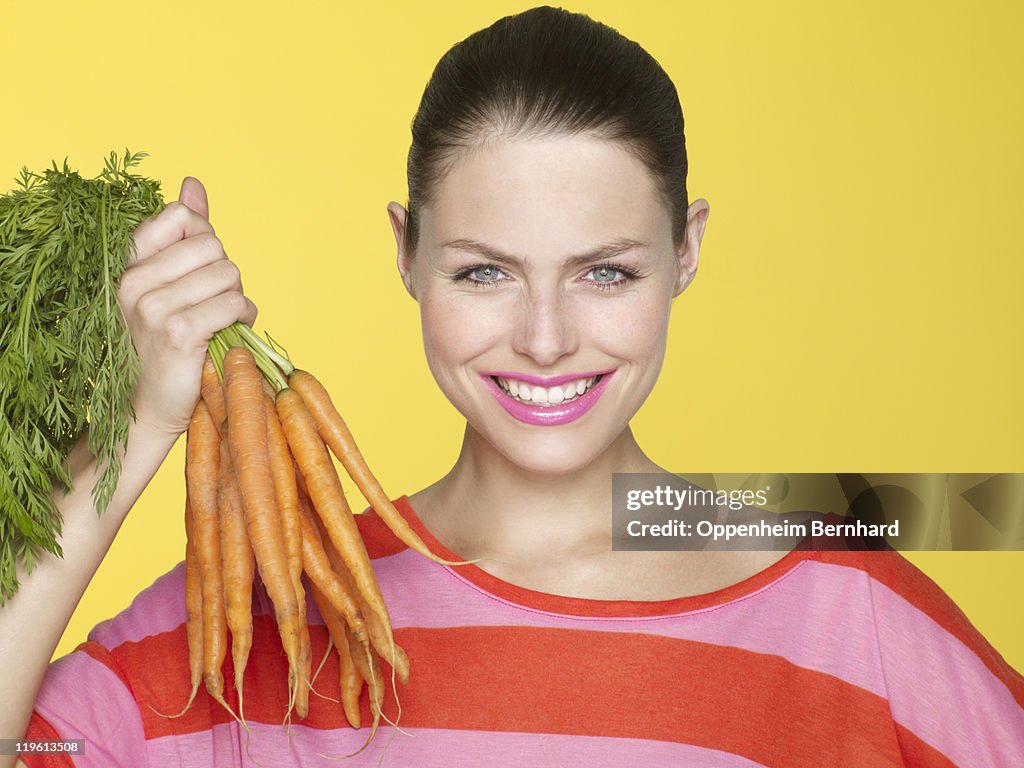 Young woman holding bunch of carrots