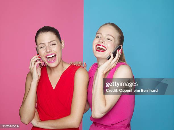 two laughing women on mobile phones - red and pink outfit stock pictures, royalty-free photos & images