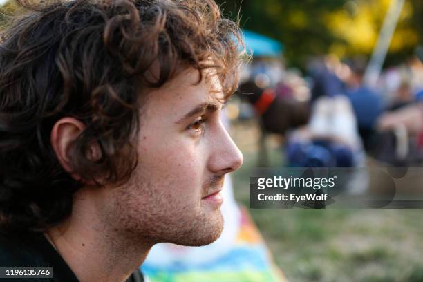 a young man sitting in the grass at a music festival - music festival day 1 stock-fotos und bilder
