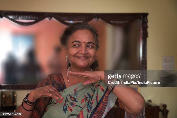 portrait of a senior woman dancing in the living room at home. - bharatanatyam dancing stockfoto's en -beelden