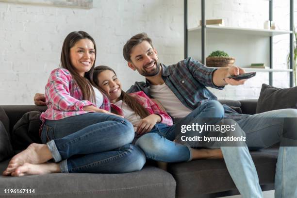 familie beim fernsehen - mutter kind lachen zuhause stock-fotos und bilder