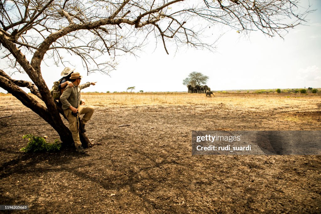 Achteraanzicht van twee Aziatische paar op gras wanneer Verken Wildernisgebied