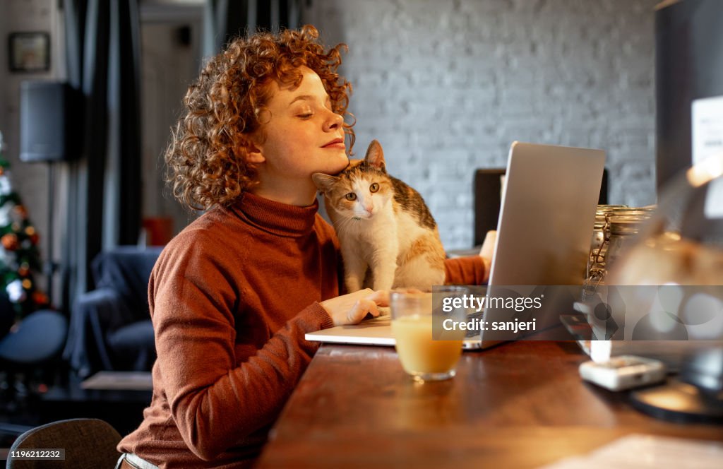 Young woman with cat using laptop