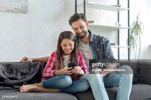 gelukkige vader en dochter met behulp van telefoon samen - family looking at smartphone stockfoto's en -beelden