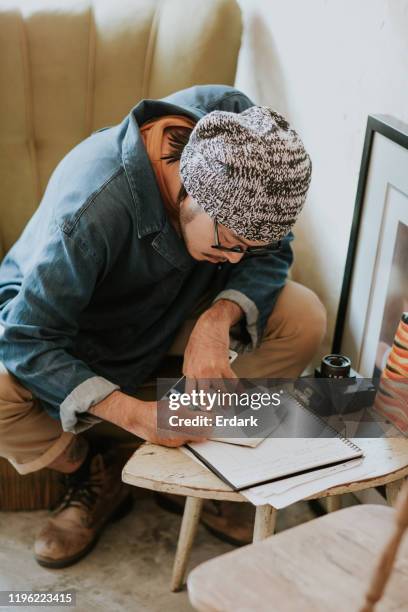 young serious bearded asian men blogger dressed smart casual writing notes in agenda while sitting in cafe - memories text stock pictures, royalty-free photos & images