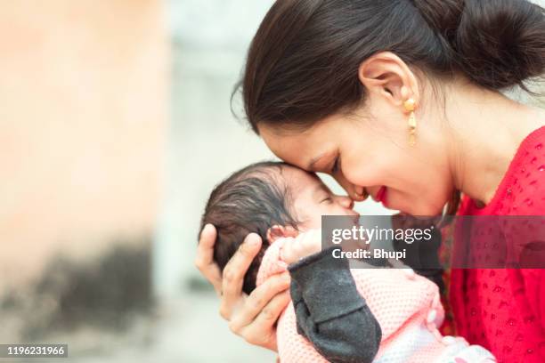 een jonge moeder is liefdevolle haar pasgeboren baby - indian mother stockfoto's en -beelden