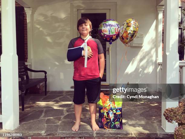 little boy with arm in sling and get well balloons - cabestrillo de brazo fotografías e imágenes de stock