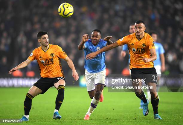 Raheem Sterling of Manchester CIty is tackled by Ruben Vinagre and Romain Saiss of Wolverhampton Wanderers during the Premier League match between...