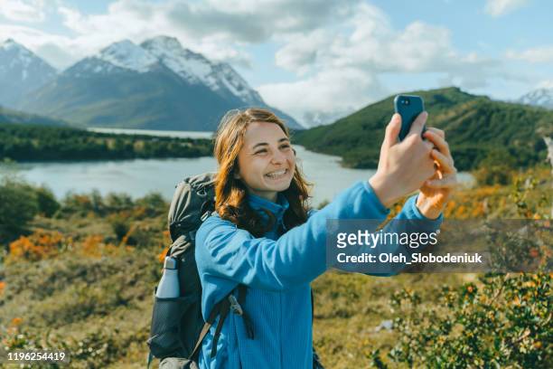frau mit rucksack macht selfie in der nähe des sees in torres del paine nationalpark - chile stock-fotos und bilder