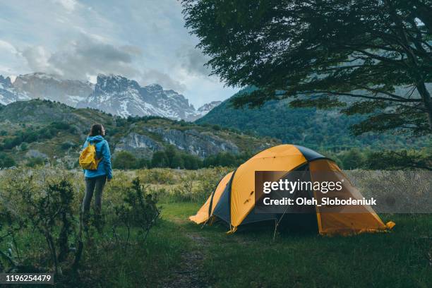 frau steht in der nähe des zeltes auf dem campingplatz in den bergen in torres del paine nationalpark - anden stock-fotos und bilder