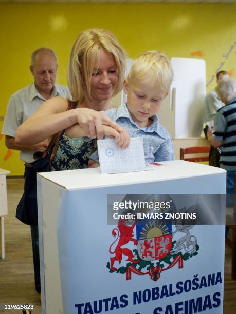 Woman casts her vote with her kid at a poling sation in Riga on July 23, 2011 during a referendum for or against the dissolution of parliament....