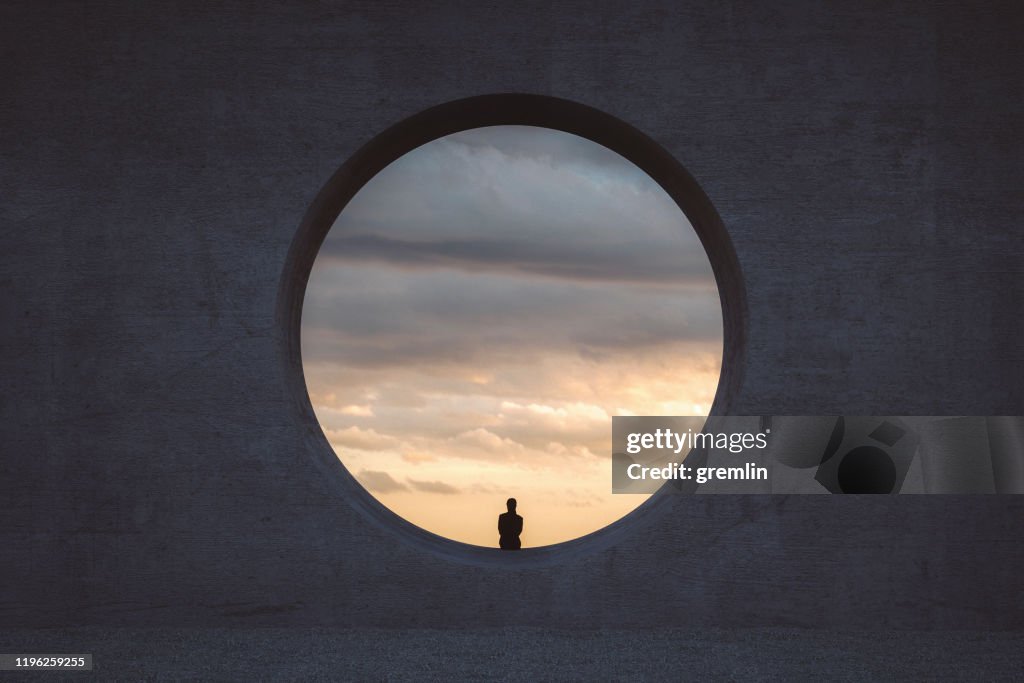 Joven solitaria mirando a través de la ventana de hormigón
