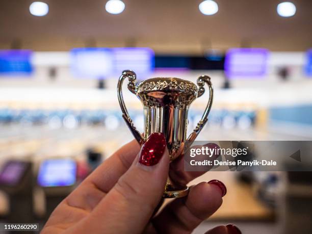 miniature trophy held in woman's hand - small victory stock pictures, royalty-free photos & images