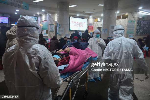 In this photo taken on January 25 medical staff wearing protective clothing to protect against a previously unknown coronavirus arrive with a patient...