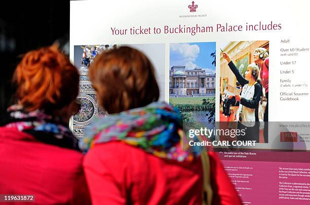 Tourists look at an information sign outside Buckingham Palace in central London as the palace opens its doors to the public for the summer on July...