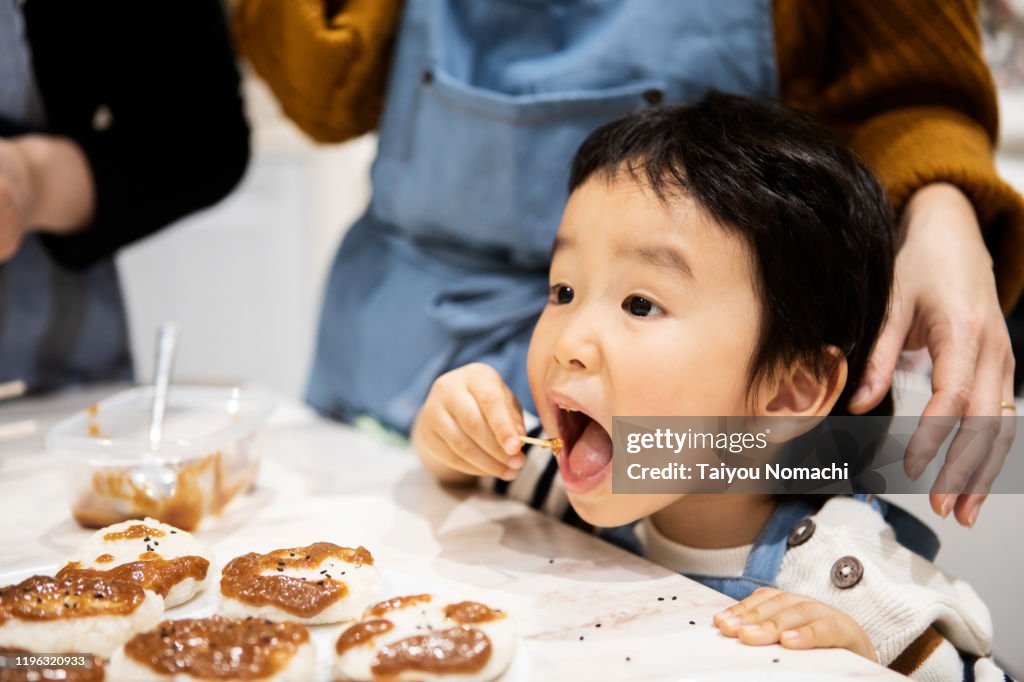 A boy eating a toothpick with miso