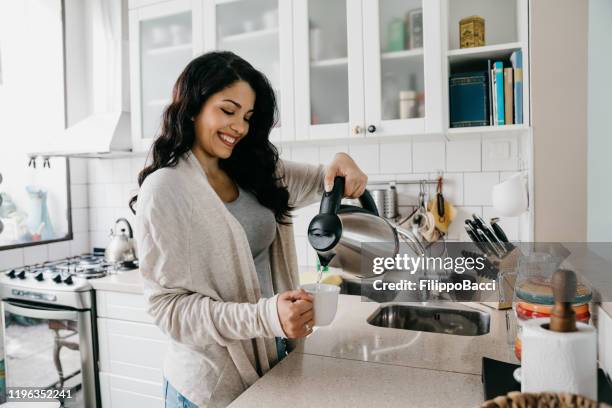 jong volwassen vrouw het vullen van een kopje koffie - ketel stockfoto's en -beelden