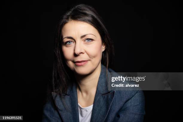 zuversichtliche reife frau vor schwarzem hintergrund - studio portrait dark background stock-fotos und bilder