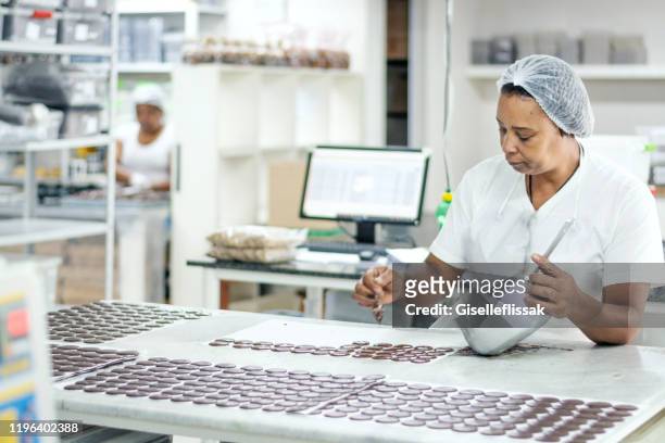 vrouw bereidt chocolade in een fabriek - chocolate factory stockfoto's en -beelden