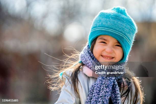 beautiful three-year-old mixed race girl smiling and playing in her backyard dressed up warmly for winter fun - sweater weather stock pictures, royalty-free photos & images