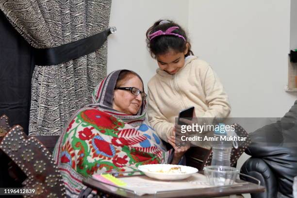 grandmother learning how to use mobile phone from her granddaughter - panyab pakistán fotografías e imágenes de stock