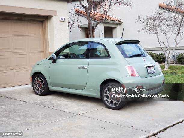 Side view of lime green Fiat 500 automobile parked on a suburban driveway in San Ramon, California, December 26, 2019. Fiat Chrysler and the owner of...
