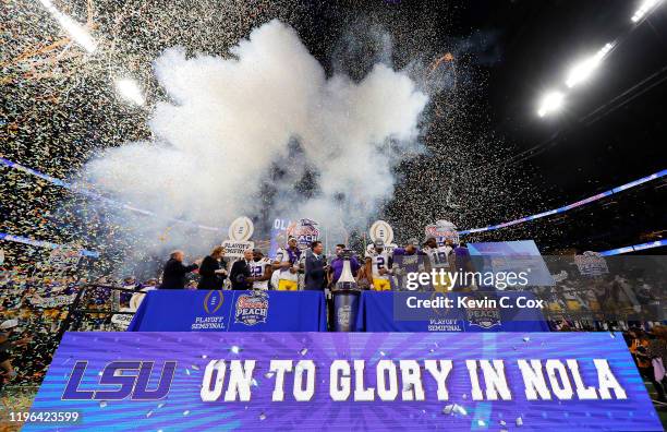 Head coach Ed Orgeron of the LSU Tigers and team celebrate on the podium after winning 28-63 over the Oklahoma Sooners in the Chick-fil-A Peach Bowl...