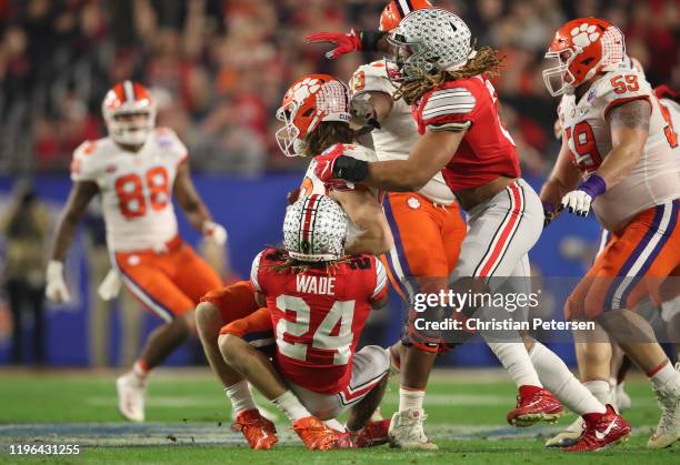 Trevor Lawrence of the Clemson Tigers is hit by Shaun Wade and Chase Young of the Ohio State Buckeyes in the first half during the College Football...