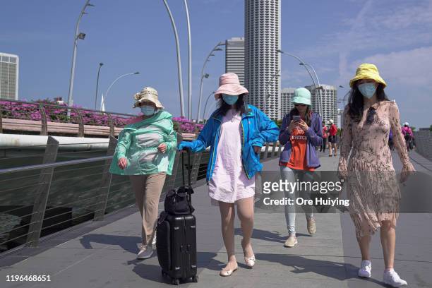 Visitors wearing masks walk through the Merlion Park on January 26, 2020 in Singapore. Singapore has confirmed four cases of the deadly coronavirus,...