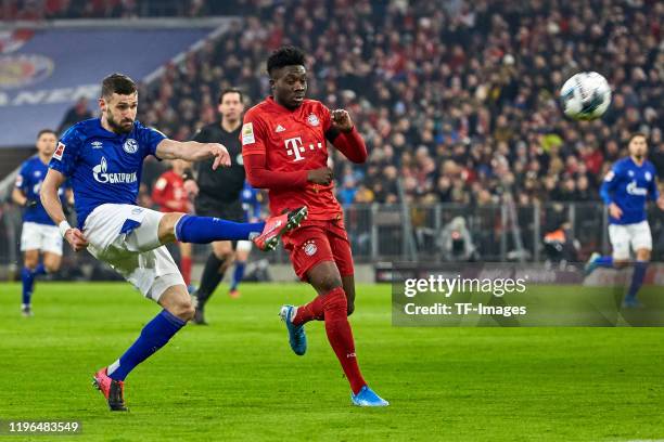 Daniel Caligiuri of FC Schalke 04 and Alphonso Davies of FC Bayern Muenchen battle for the ball during the Bundesliga match between FC Bayern...