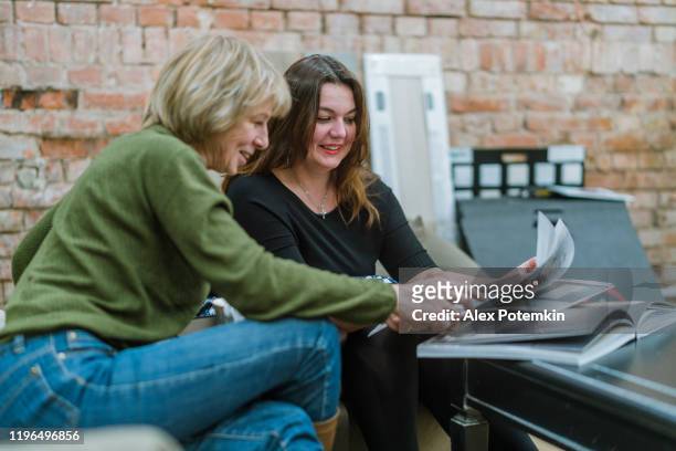 dos mujeres de negocios, de 30 años y 50 años, discutiendo algún proyecto en la moderna oficina de freestyle - 50 54 years fotografías e imágenes de stock