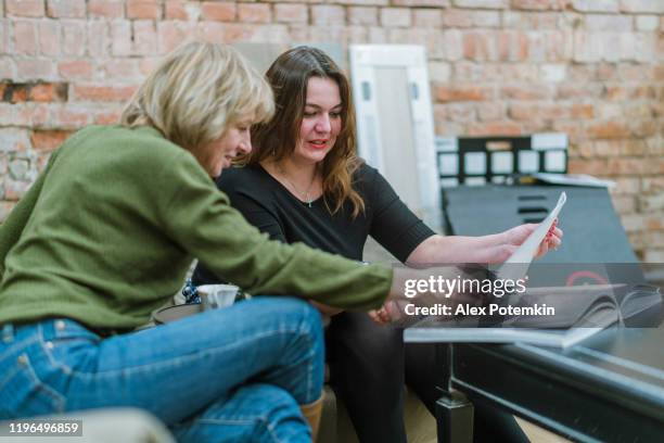 two businesswomen, 30 years old and 50 years old, discussing some project in the modern freestyle office - woman 30 years old portrait stock pictures, royalty-free photos & images