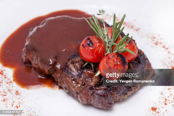 grilled steak with dark sauce and cherry tomatoes on the plate - beefsteak 2013 stock pictures, royalty-free photos & images