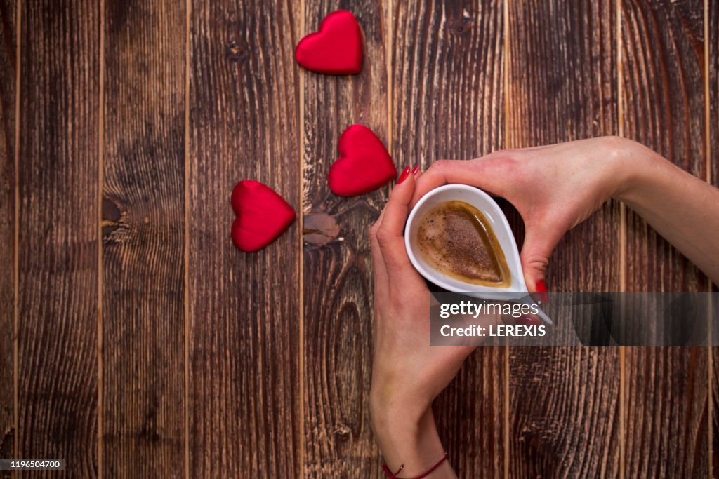 Female hands holding cup of coffee on Valentine's morning